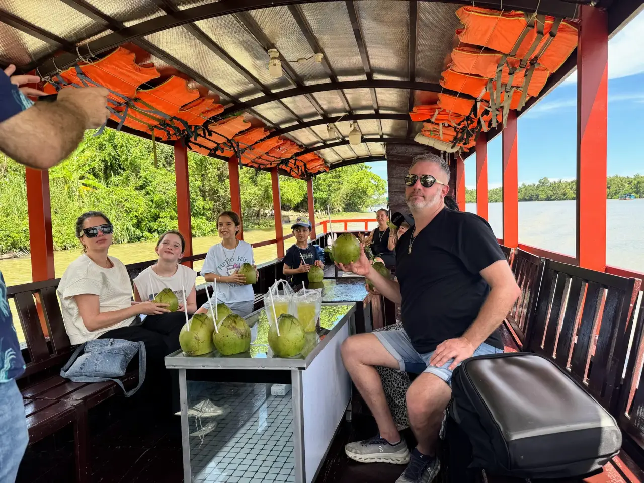 Guests sharing fresh coconut on a wooden boat