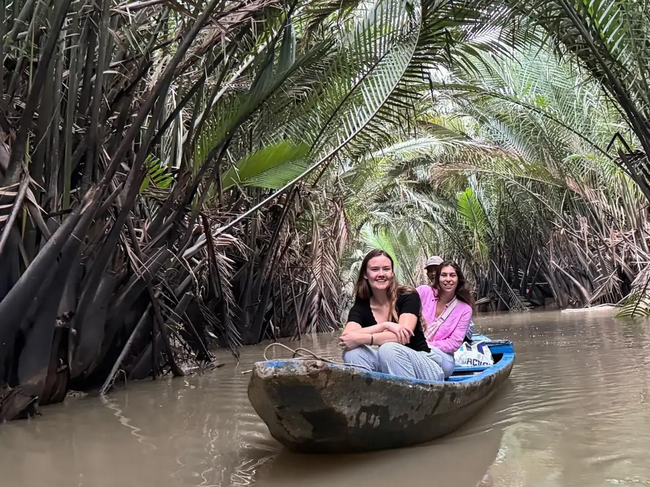 Traditional hand-rowed sampan on a nipa-palm canal in Ben Tre